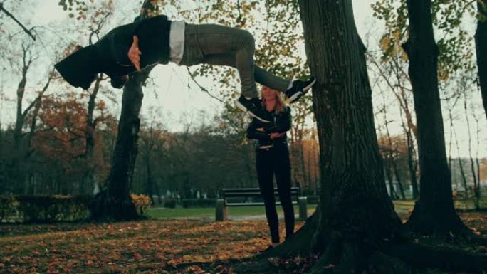 SLO MO年轻人在女友面前表演了一棵树的后空翻