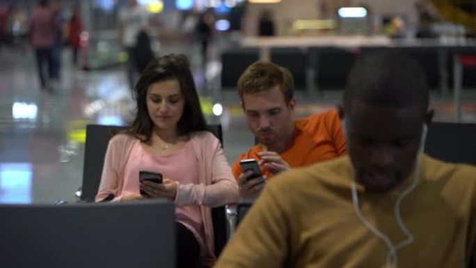 使用智能手机在机场等待航班的多样化乘客