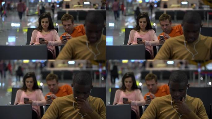 使用智能手机在机场等待航班的多样化乘客