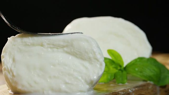 宏观拍摄新鲜的意大利马苏里拉奶酪和充满牛奶的生物，背景是红色西红柿和罗勒。