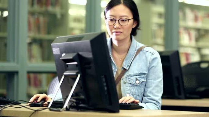 年轻的韩国妇女在图书馆使用计算机