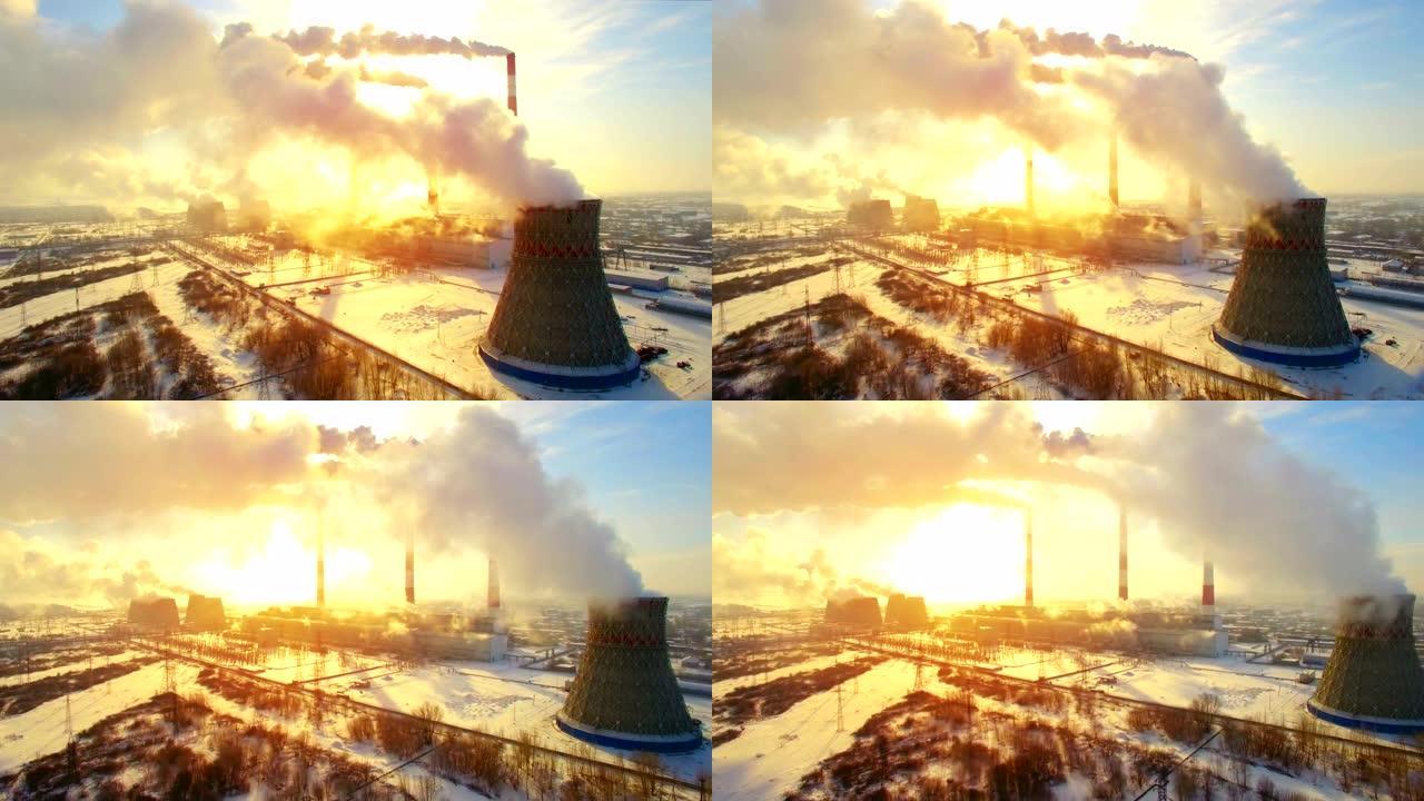 火力发电厂周围超高速的空中全景飞行。冬天的二氧化碳排放，烟雾和蒸汽的能量，阳光透过烟雾的云层照射。生