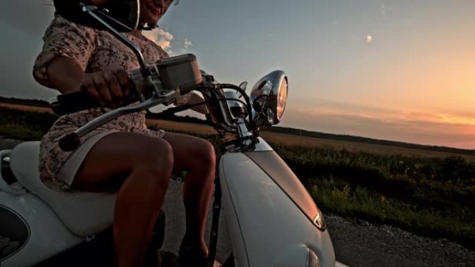 日落时骑踏板车的超级SLO MO女人