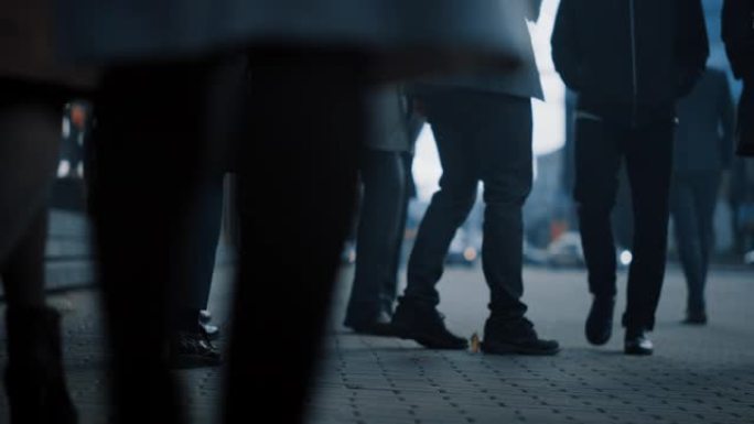 一个商务人士步行通勤到办公室的特写镜头。经理和商人走在拥挤的步行街上。市中心阴天。