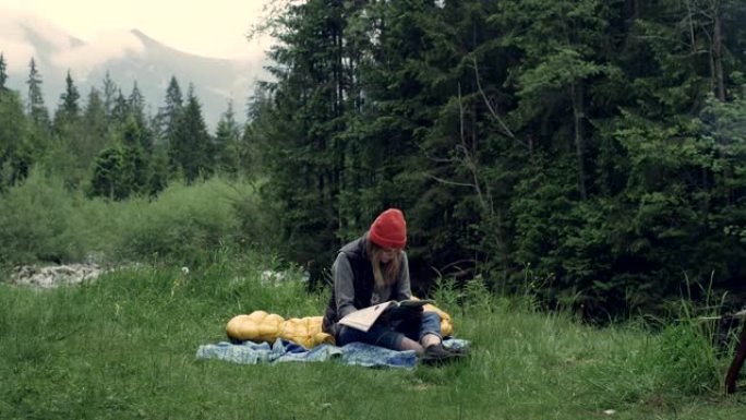 在野外露营。女人在草地上读书