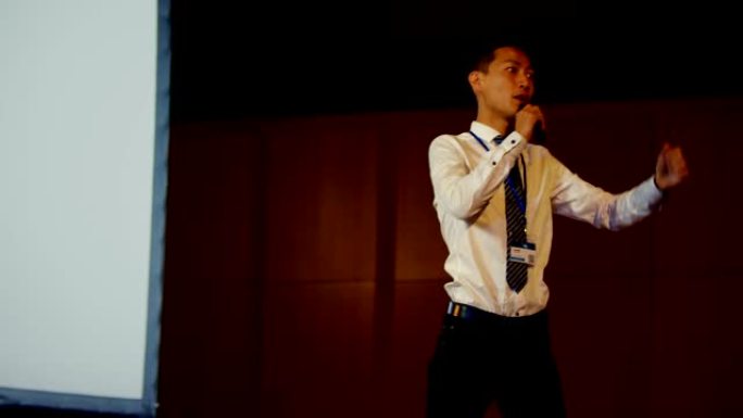 年轻的亚洲商人在4k礼堂的商业研讨会上发言