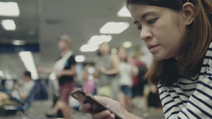 时髦的女人在机场候机室等候登机时使用智能手机。