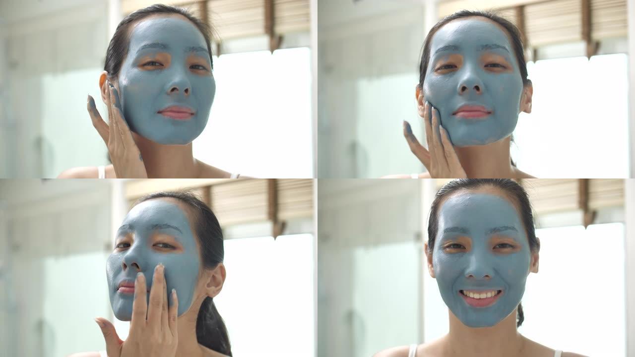 亚洲人在脸上戴上蓝色保湿面膜，看着家里浴室里的相机