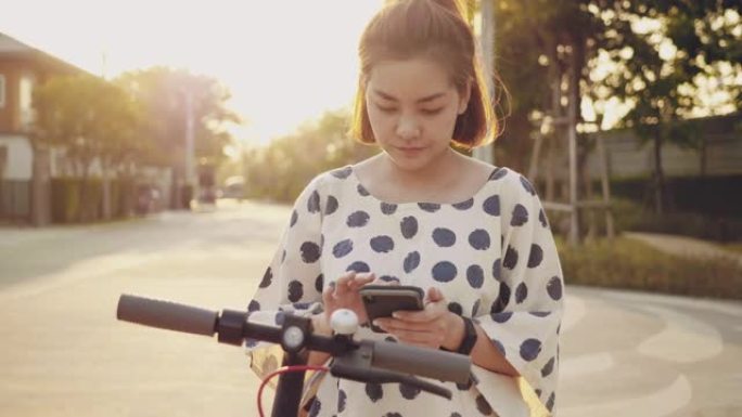 年轻女子用手机解锁电动推动踏板车