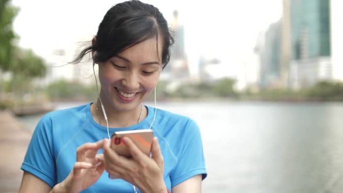 运动女人使用智能手机，在智能手机上听音乐
