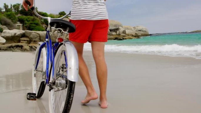 白人男子在海滩上骑自行车行走的后视图4k