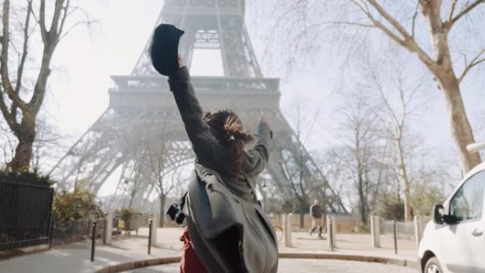 摄像机跟随快乐美丽的女人兴奋地看到著名的埃菲尔铁塔，在巴黎大街上快乐地旋转慢动作