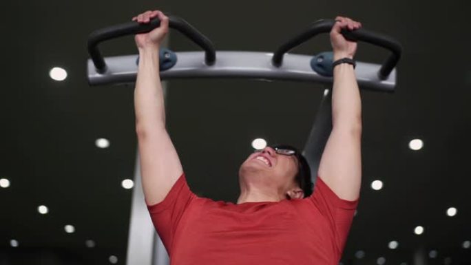 亚洲男子试图在健身房用引体向上锻炼背部
