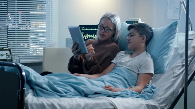 母亲与生病的儿子一起使用平板电脑