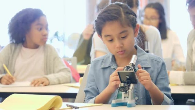 自信的小学生在课堂上使用显微镜