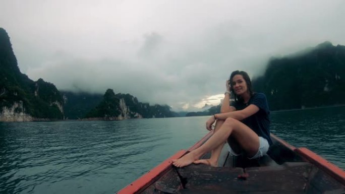 下雨时，女人坐在河上的船上。
