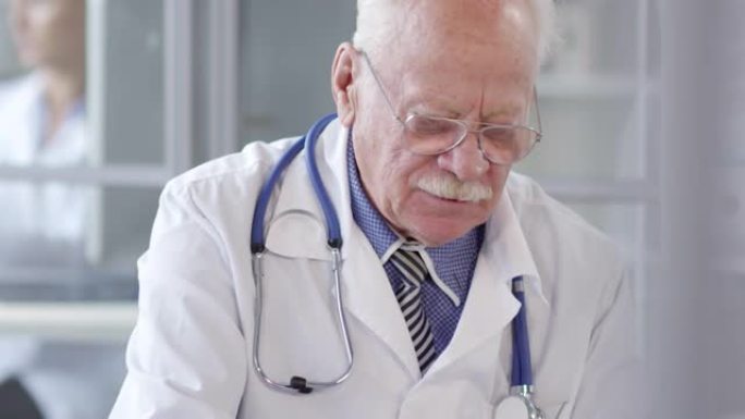 老年医生在笔记本电脑上打字并听患者讲话