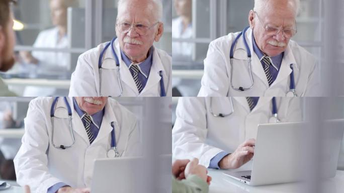 老年医生在笔记本电脑上打字并听患者讲话