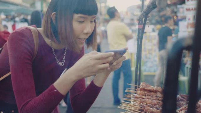 亚洲男子在街头美食上烧烤拍照