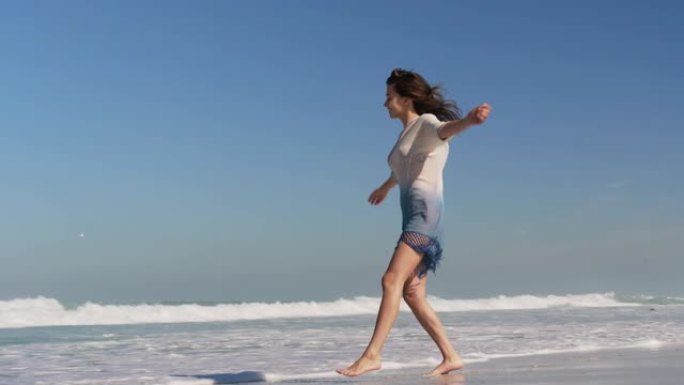 年轻女子在阳光下的海滩上跳舞4k