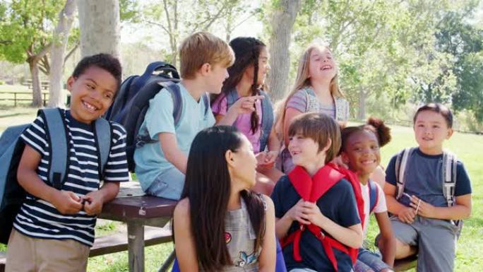 一群孩子和朋友在公园里围坐在桌子旁慢动作拍摄