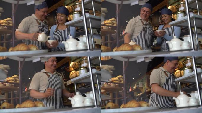 企业主在面包店为顾客提供咖啡，同时非常愉快地交谈-通过玻璃拍摄