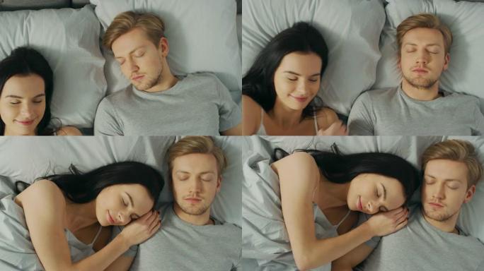可爱的年轻夫妇甜蜜地睡在床上，一边做梦，一边温柔地拥抱着彼此。清晨的阳光透过窗户照射。