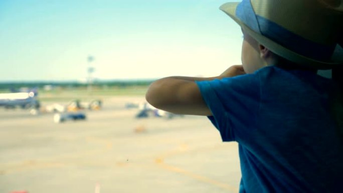 一个看飞机的孩子，特写。一个男孩坐着看着机场跑道。
