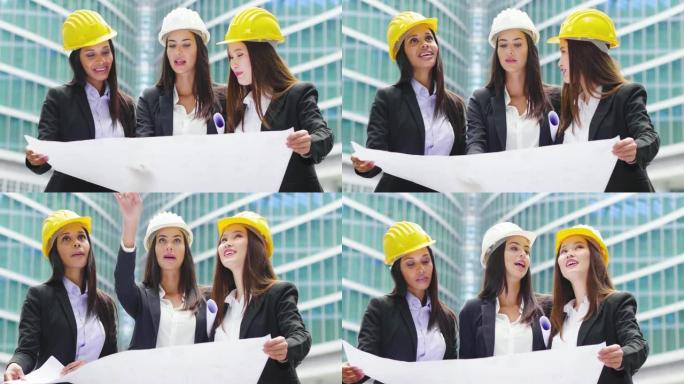 三名不同种族 (亚洲，欧洲和美国黑人) 戴着头盔的工程师妇女观看了一个建筑项目，并讨论了如何继续工作
