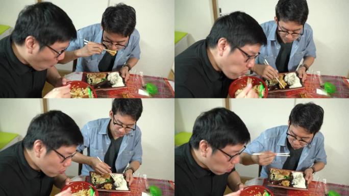 两名男子在餐桌上吃日本便当盒午餐，家庭生活