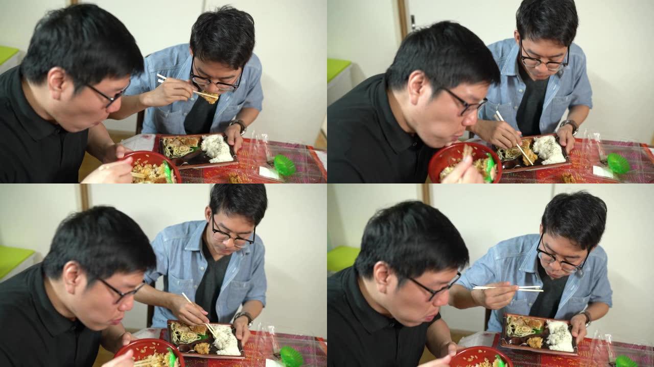 两名男子在餐桌上吃日本便当盒午餐，家庭生活