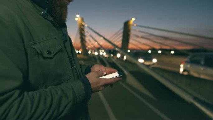 Man女士在黄昏时在桥上使用智能手机