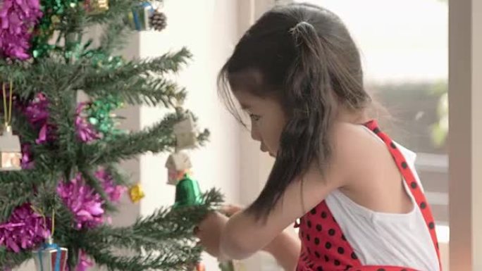 寒假传统: 圣诞快乐，节日快乐!。小女孩在室内装饰圣诞树。圣诞节前一天早上。