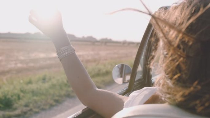 CU SLO MO无忧无虑的年轻女子沿着阳光明媚的乡村道路驾驶敞篷车