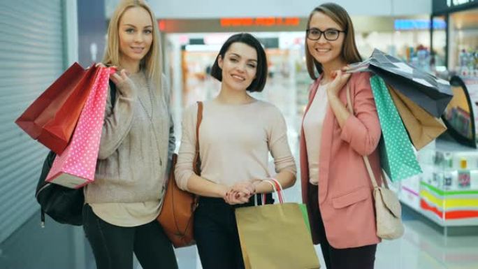 快乐女孩购物者的肖像，彩色纸袋站在购物中心里，看着相机，微笑着。青年生活方式和商店概念。