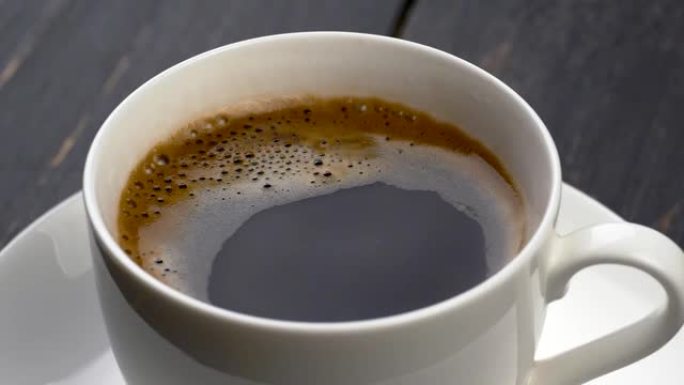 一滴滴咖啡掉进了咖啡杯里。黑色木质背景。慢动作镜头