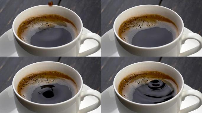 一滴滴咖啡掉进了咖啡杯里。黑色木质背景。慢动作镜头