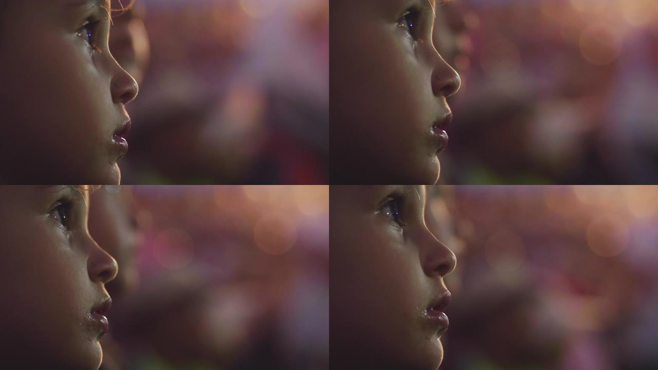 一个小女孩的脸的特写镜头，用灯光效果观看节目。