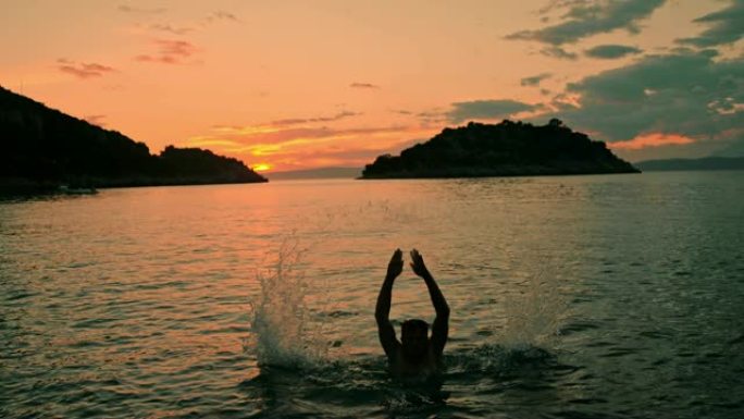 旺盛的男子女士在日落时跳出宁静的海洋，克罗地亚佩列萨克