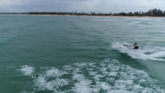 4k空中特写侧视图，男子在莫桑比克海洋中的个人船只上跳过海浪