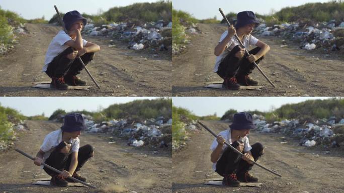 男孩蹲在非法垃圾填埋场