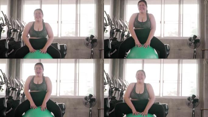 微笑的胖女人在健身房的普拉提球上锻炼