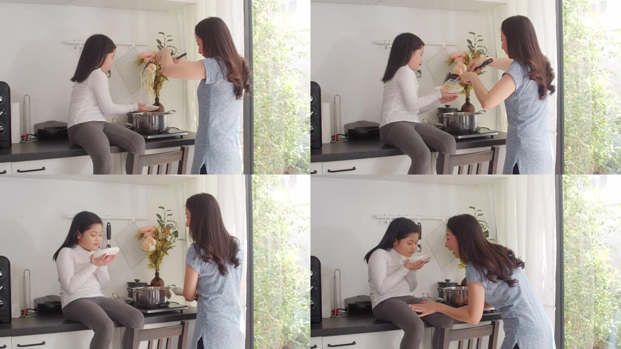 亚洲日本妈妈和女儿在家做饭。生活方式的女性很乐意在家里的厨房里一起做意大利面和意大利面作为早餐。慢动