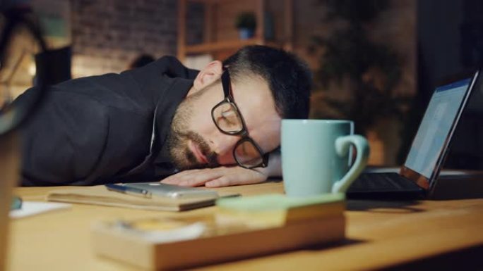同事工作时，疲惫的经理晚上在办公室的桌子上睡觉