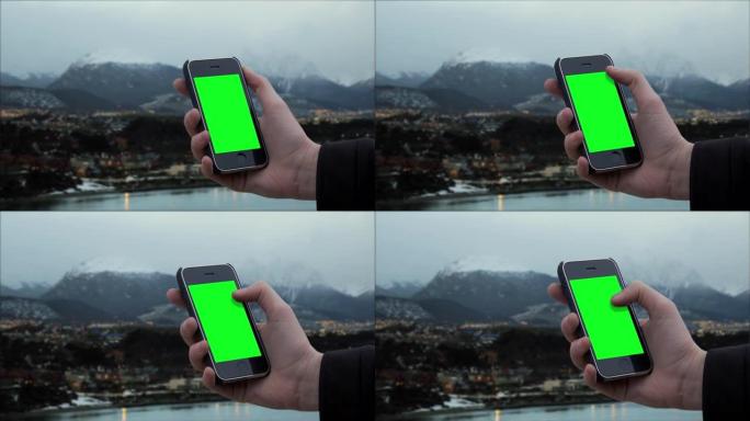 在阿根廷，巴塔哥尼亚的火地岛省乌斯怀亚市附近，男性手持智能手机绿屏。