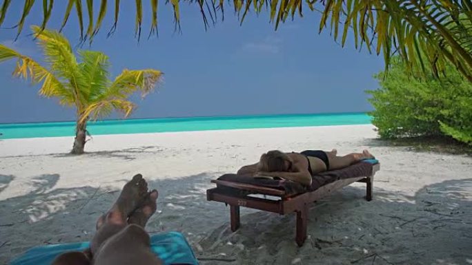 男女女士放松身心，在马尔代夫热带海洋海滩田园诗般的躺椅上小睡