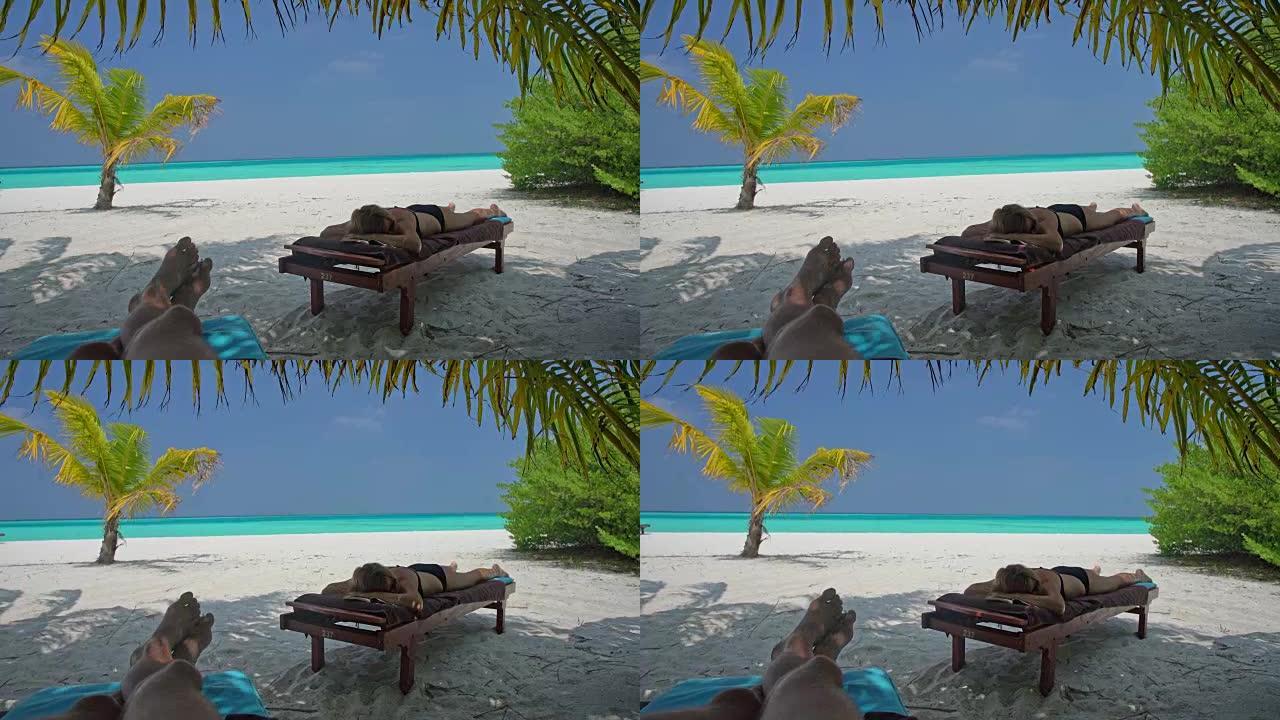 男女女士放松身心，在马尔代夫热带海洋海滩田园诗般的躺椅上小睡