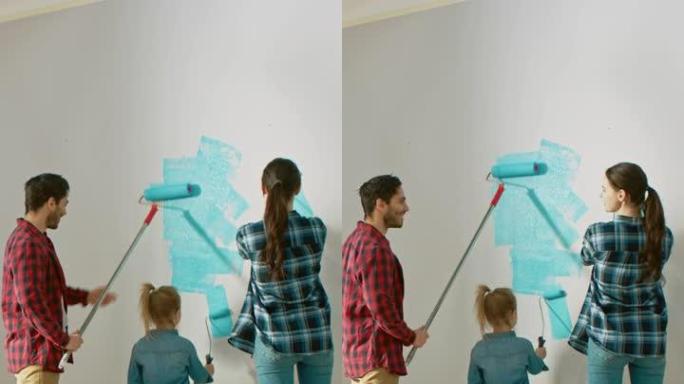 一个家庭和他们可爱的小女儿画墙壁的照片。他们用覆盖着浅蓝色油漆的滚筒涂漆。房间装修。垂直屏幕方向9: