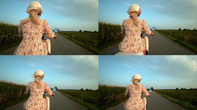 超级SLO MO女人在乡村道路上骑踏板车