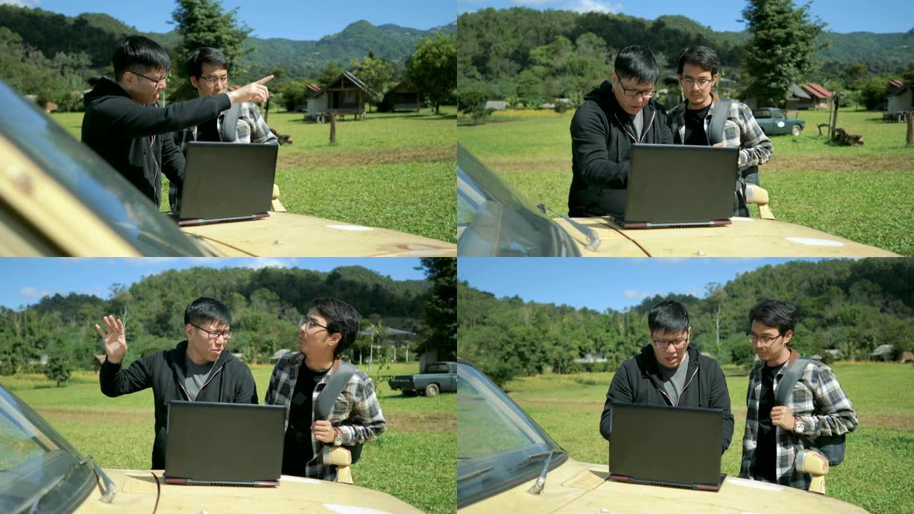 两名在户外使用笔记本电脑的亚洲男子